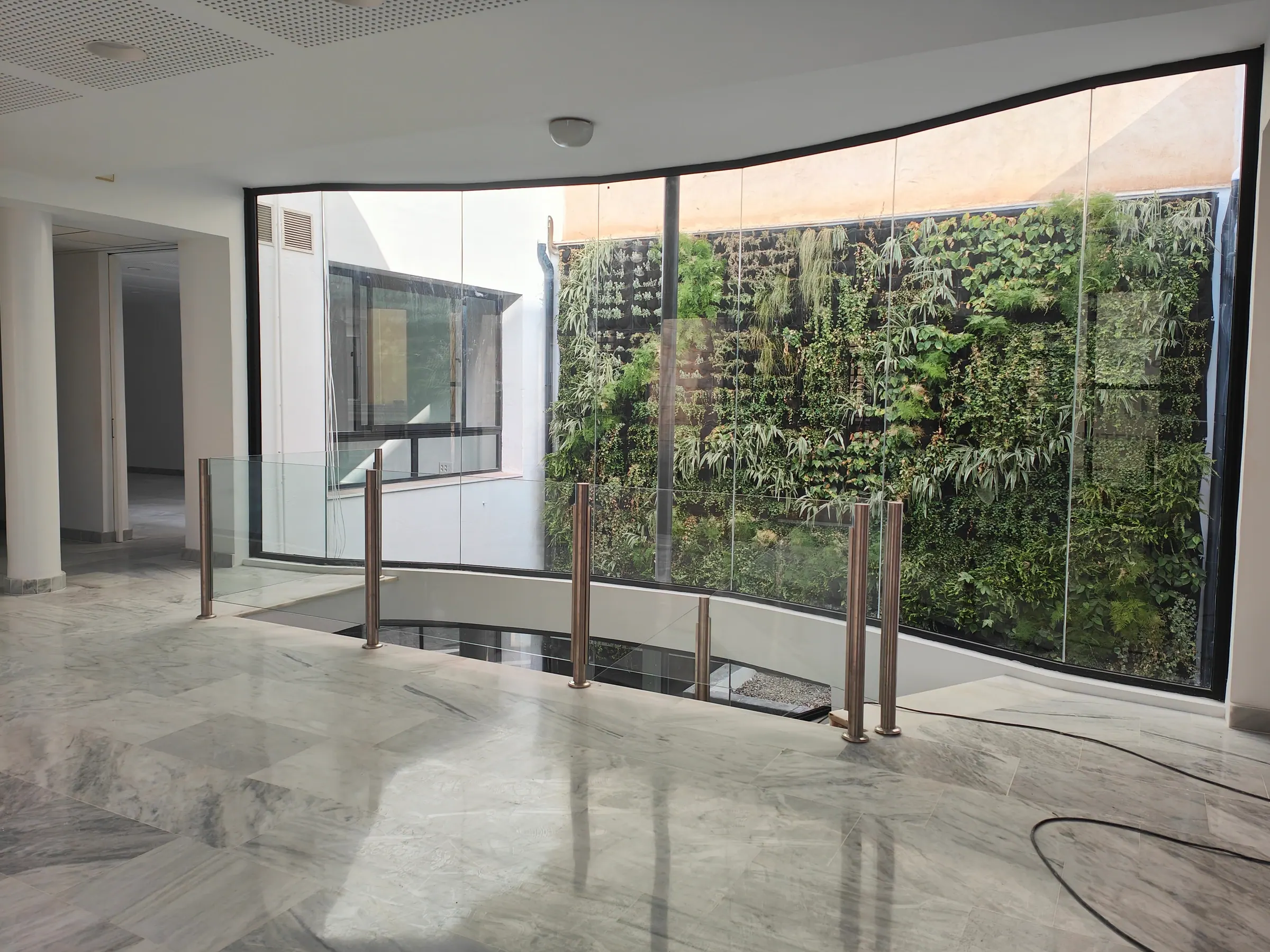 Patio interior con vegetación y cerramientos de vidrio
