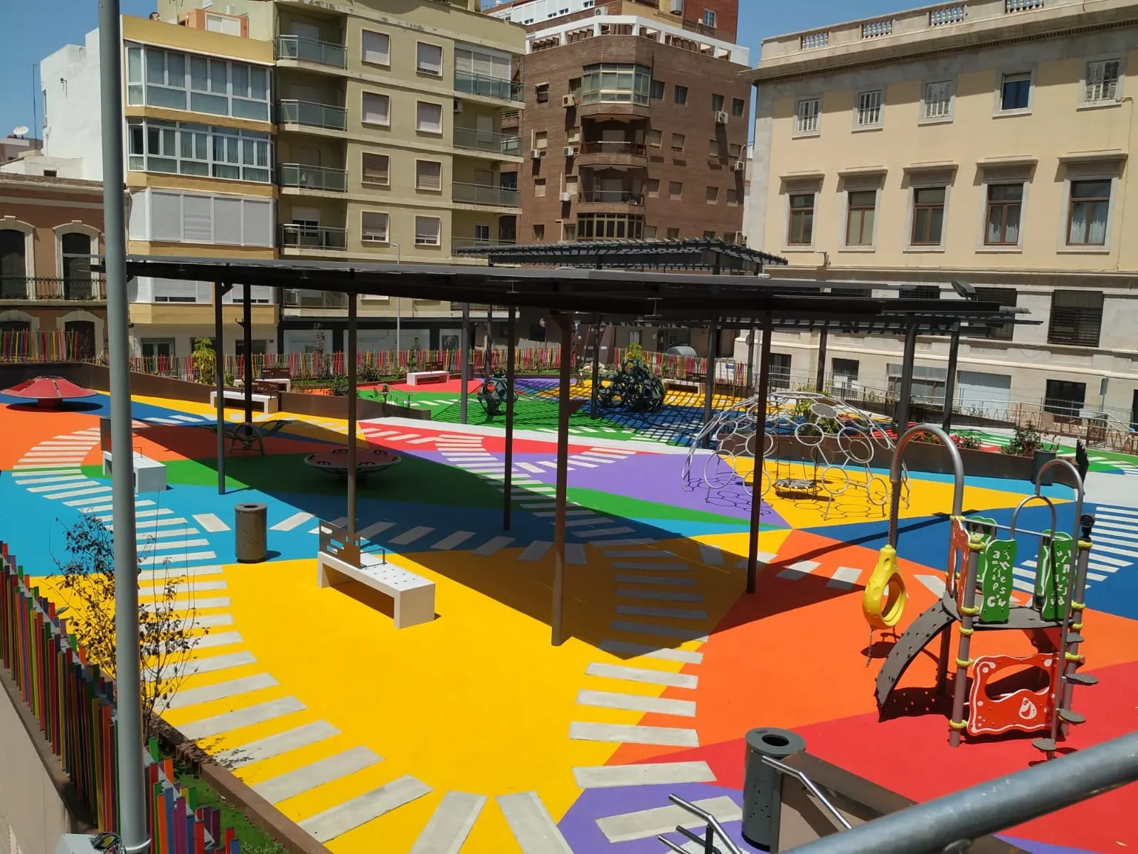 Vista general de plaza con pavimento de colores y pérgolas