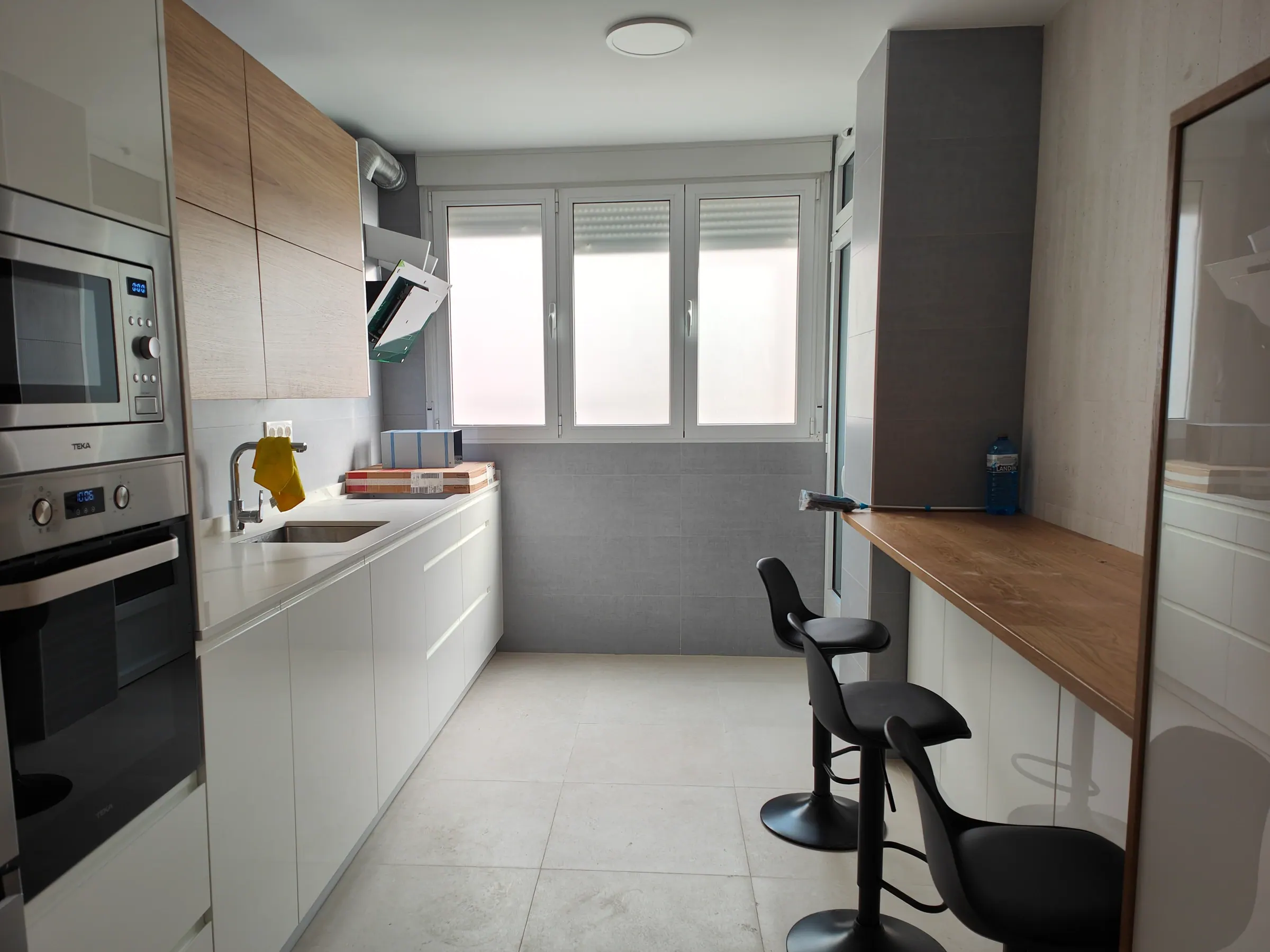 Cocina reformada con muebles claros, encimera de madera y luz natural
