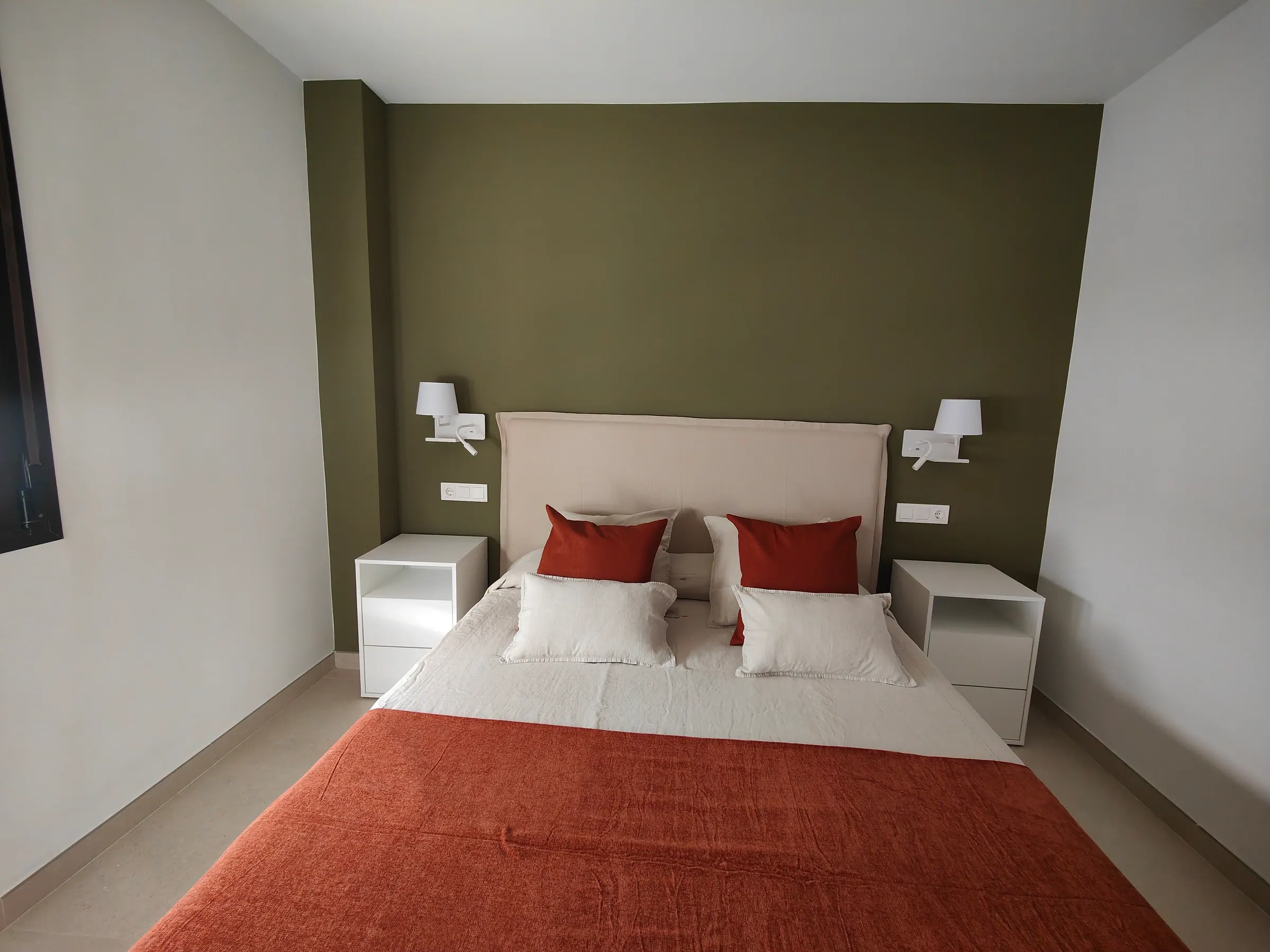 Dormitorio con pared verde y acabados cálidos