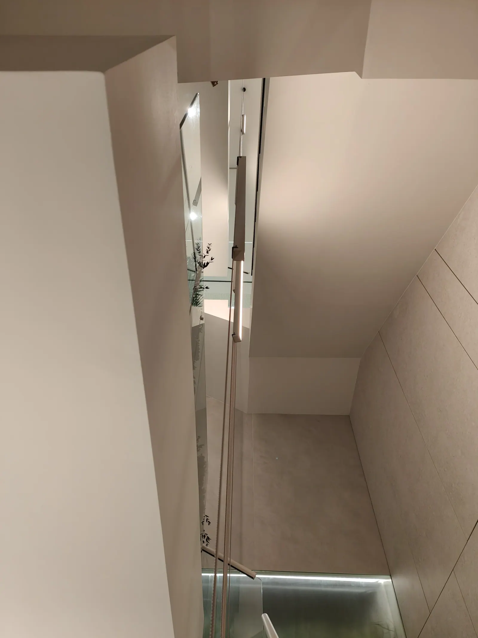 Detalle del hueco de escalera con vidrio e iluminación lineal
